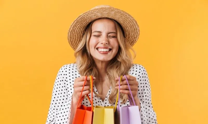 Femme souriante tenant des sacs colorés, satisfaction garantie